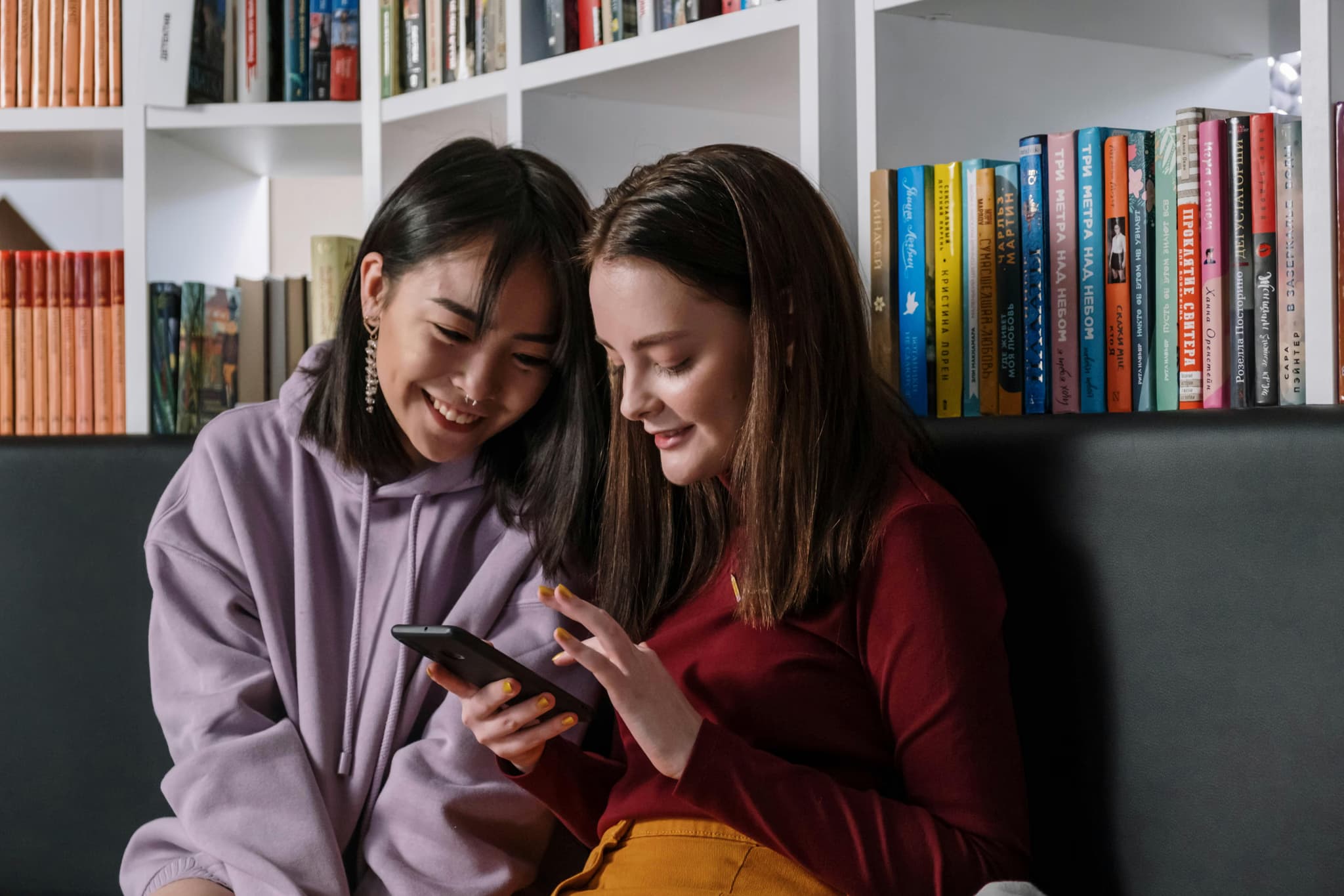 Two students smiling in front of bookshelves